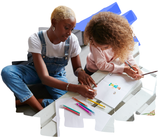 Two individuals are sitting on the floor, drawing and coloring a sheet of paper with colored pencils.