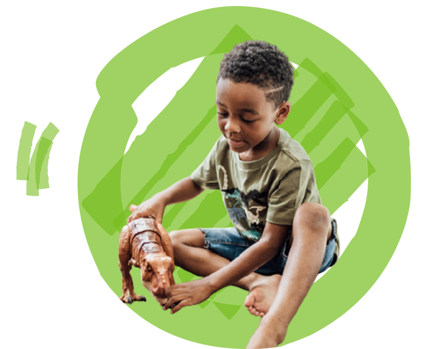 A child plays with a dinosaur toy while sitting against a vivid green circular background.