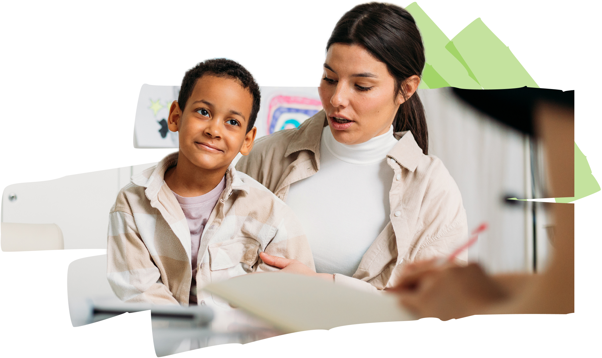 A woman is talking to a child who is smiling and sitting next to her.