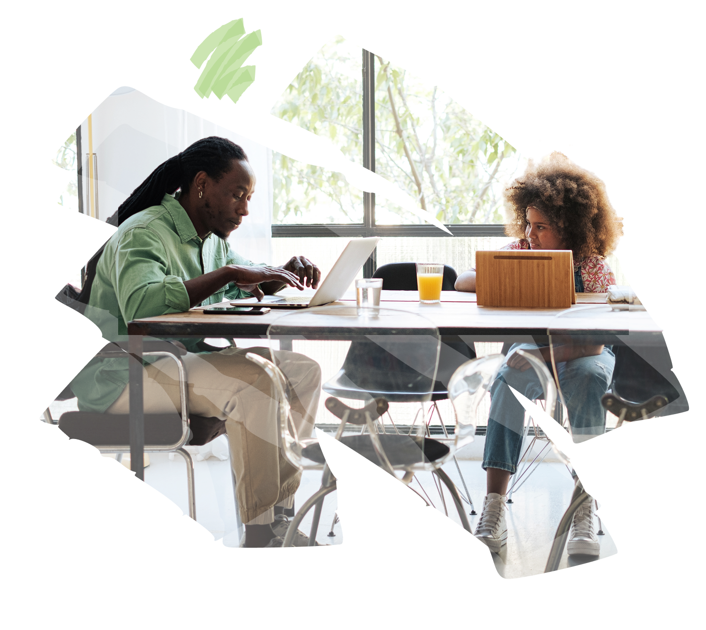 Two people are sitting at a table with laptops and drinks, engaging in a conversation.